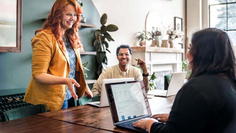 Three revenue team members gather around a conference table for a planning session.