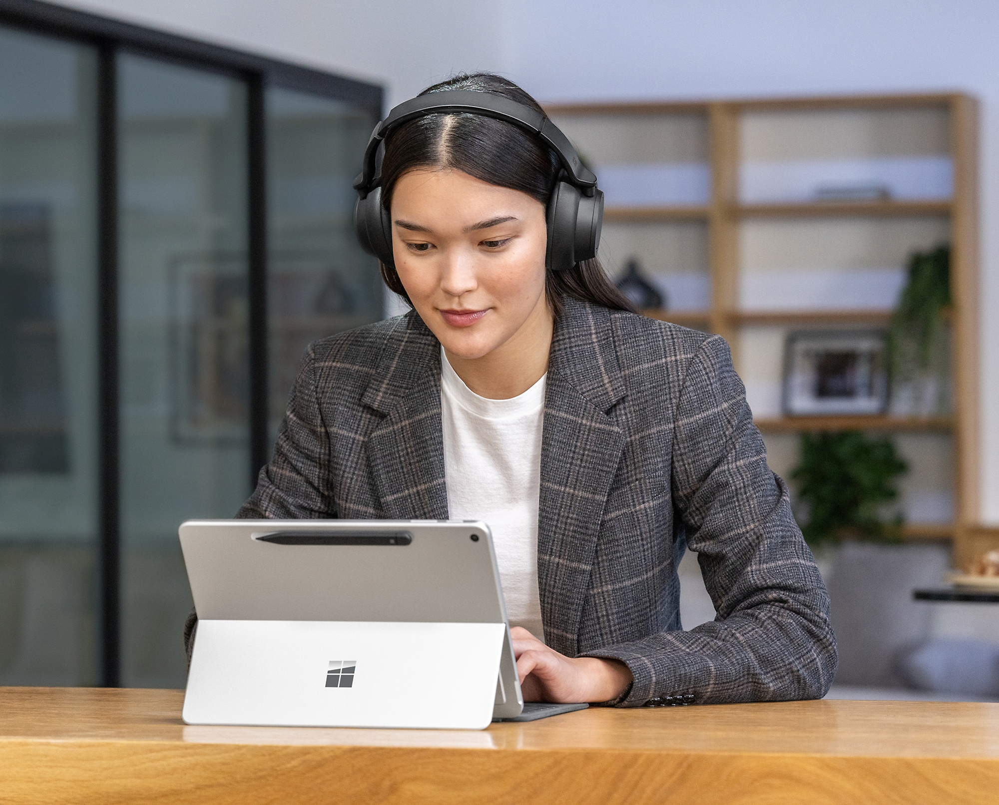 Μια γυναίκα που φοράει ακουστικά και χρησιμοποιεί tablet.