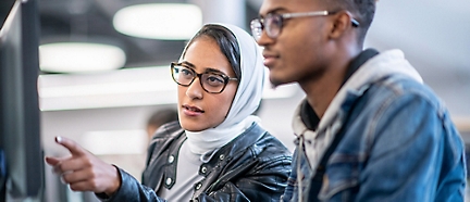 Une femme portant des lunettes et un foulard regarde quelque chose.
