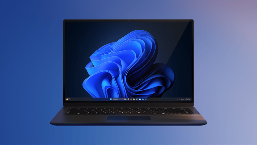 A laptop with a dark keyboard displaying Windows 11 default wallpaper of blue bloom on a dark background. The device is centered against a gradient backdrop transitioning from blue to purple. 