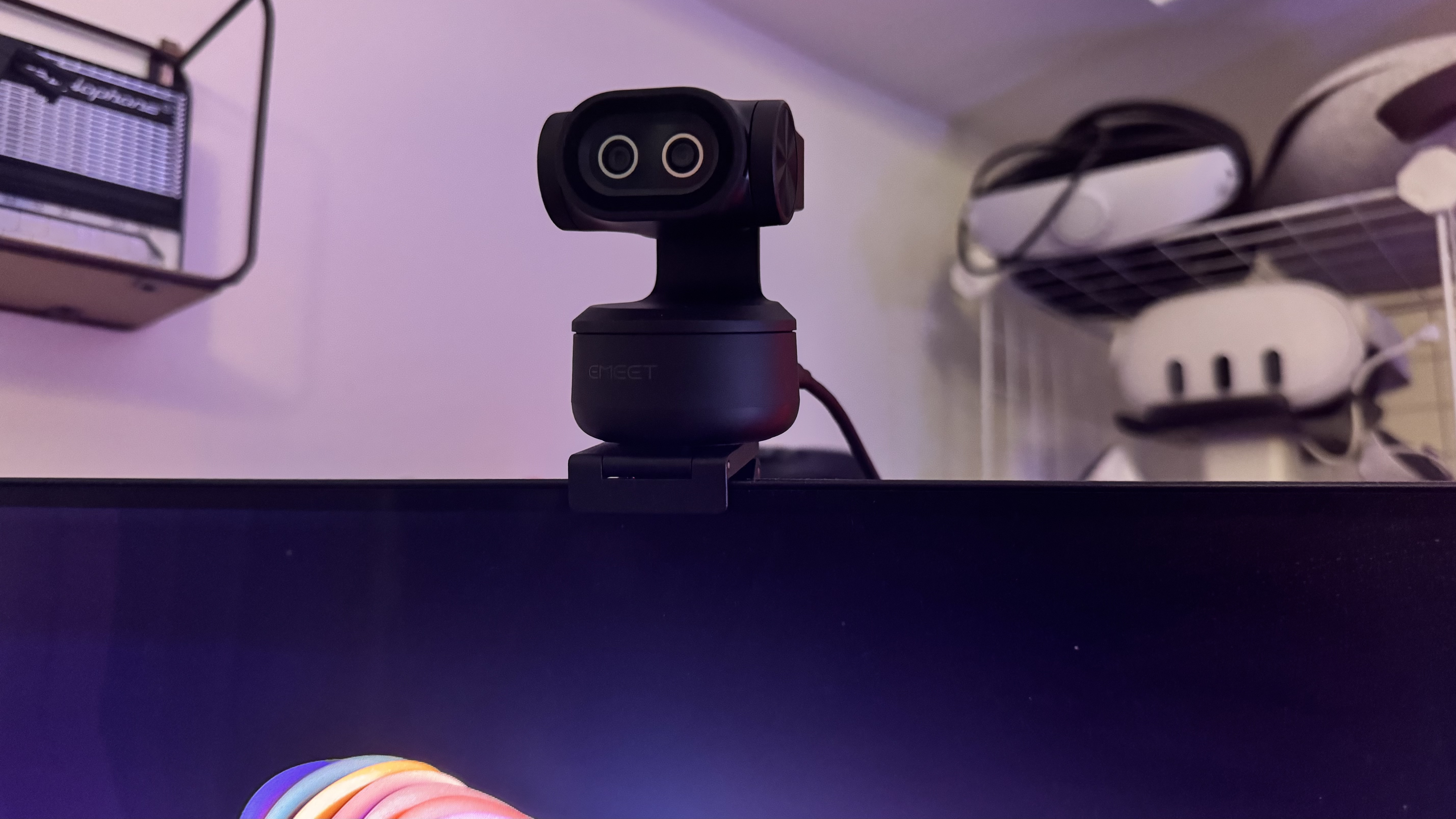 The Emeet Pixy 4K webcam on top of a webcam, with VR headsets in the background. 