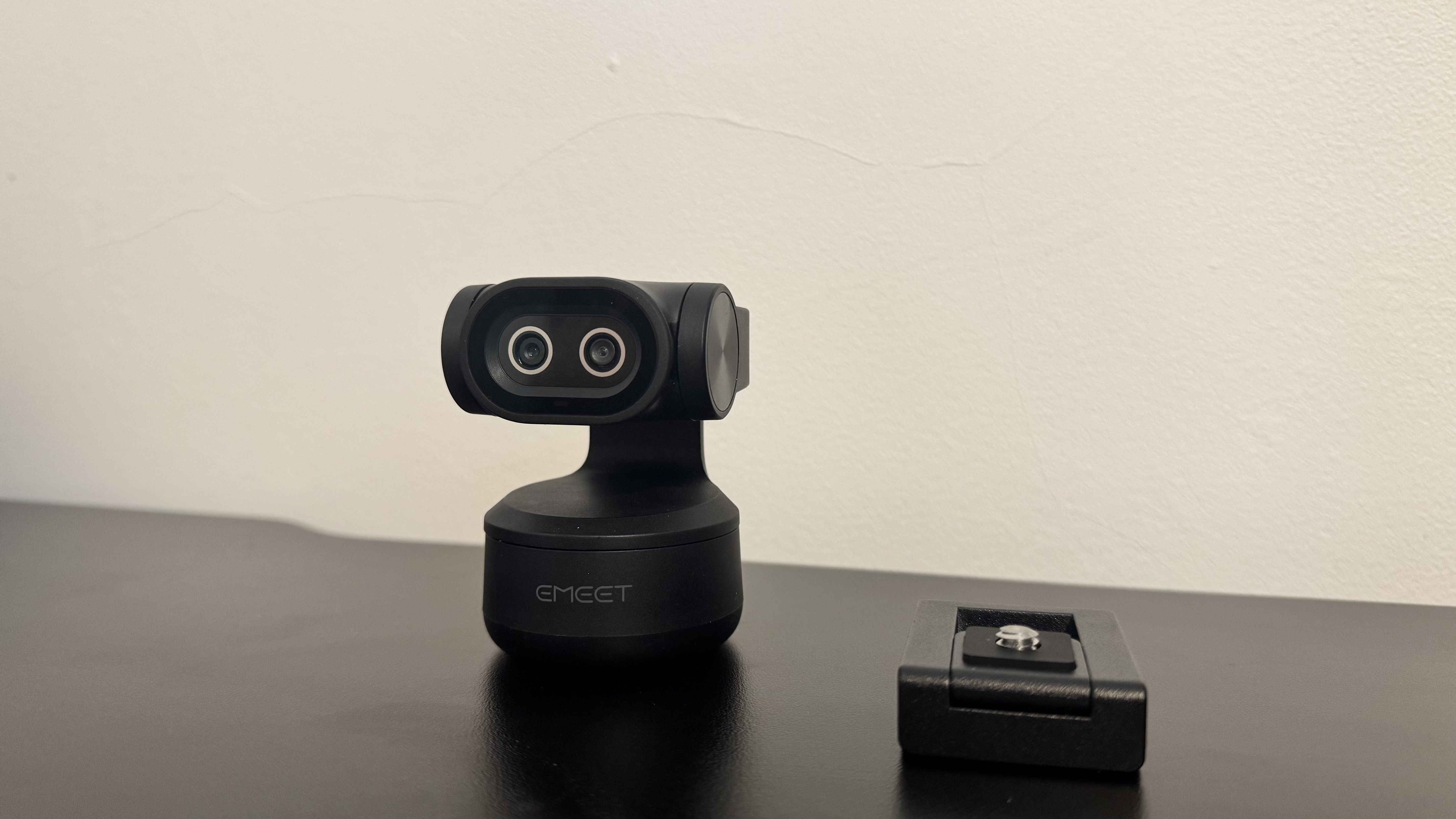 The Emeet Pixy 4K webcam and its stand, on a black desk. 