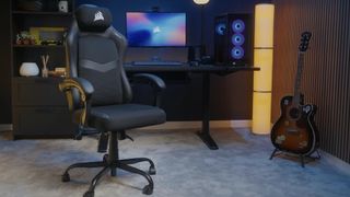 A Corsair TC80 gaming chair in a room next to a gaming PC, desk, and guitar.
