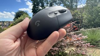 Logitech G305 X Superlight gaming mouse, held in a hand outside
