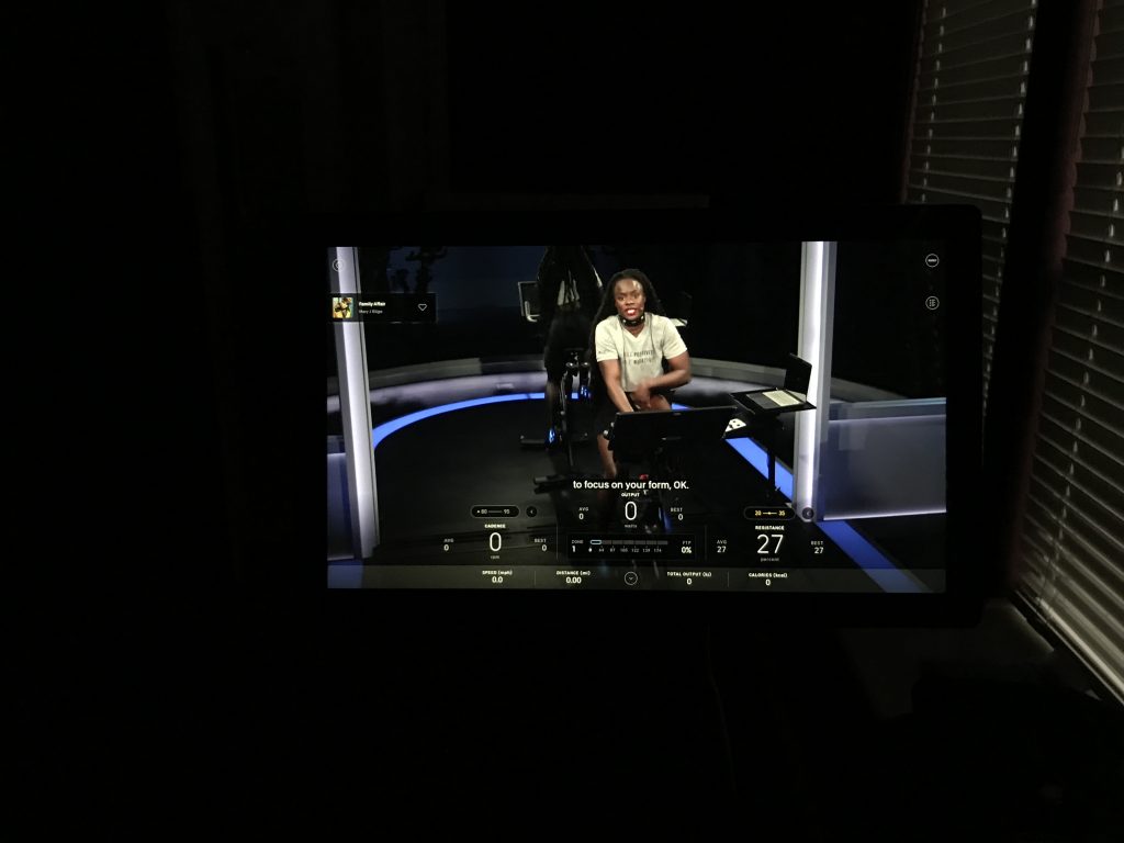 Close-up photo showing a Peloton Bike screen and an instructor with live subtitling.