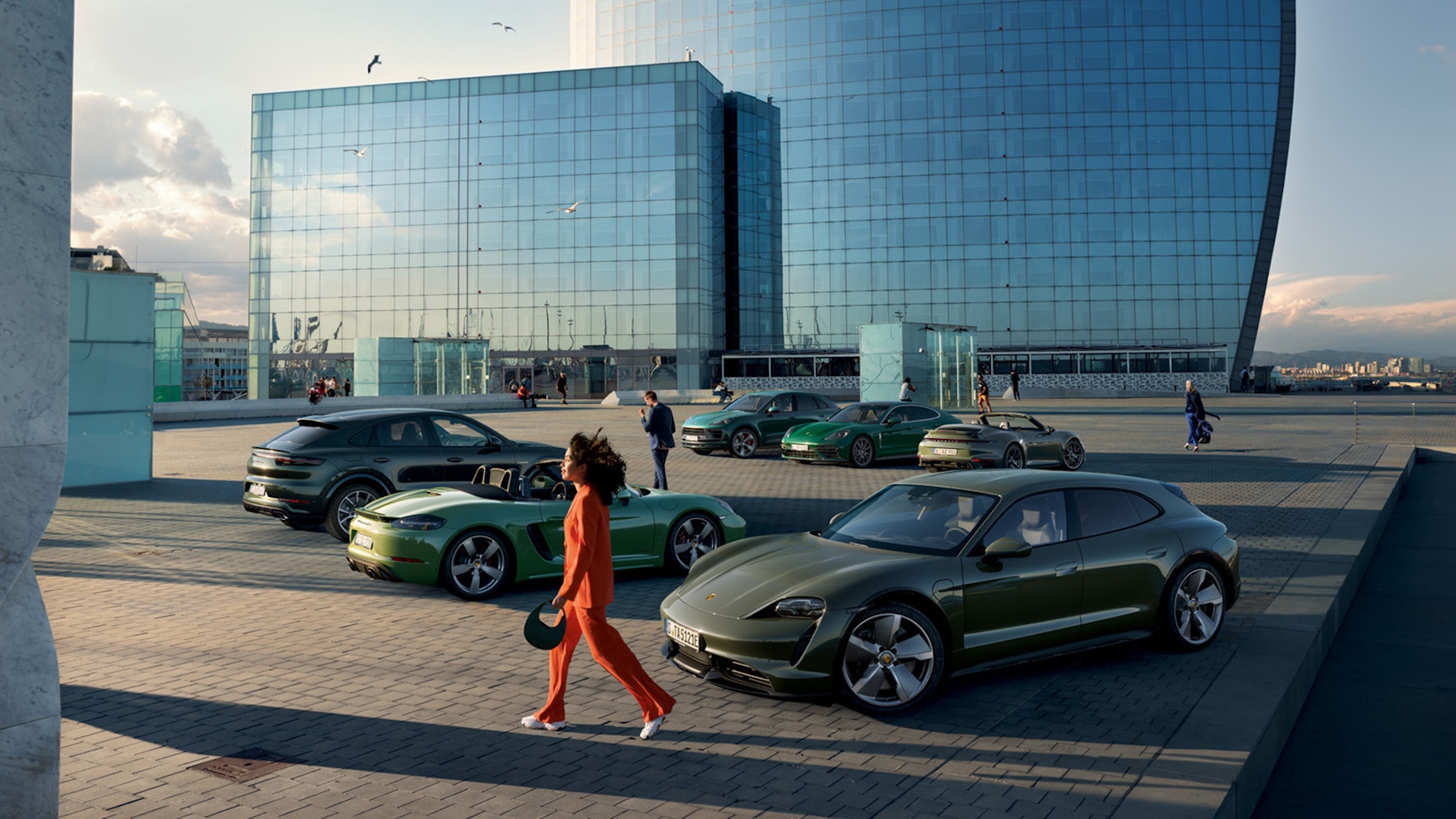 A woman walks past lined-up Porsche models of different colors.
