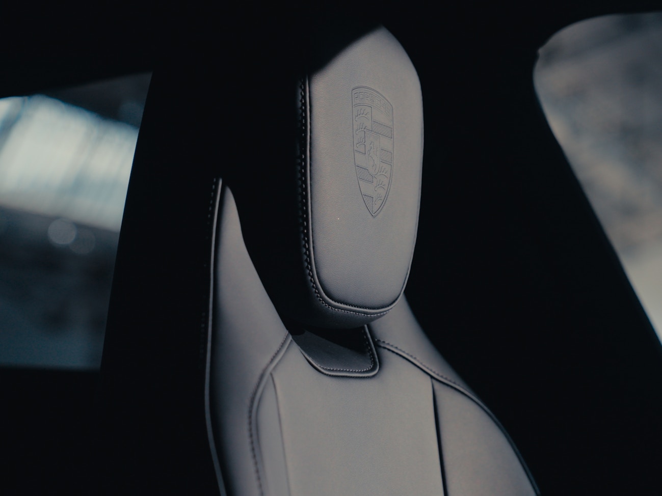 Close up of a car seat with a Porsche crest on the headrest.