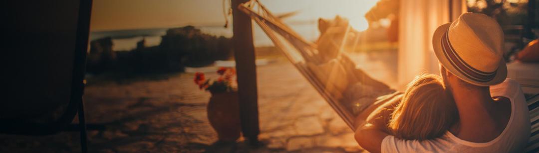A father and child together in a hammock, watching a beautiful sunrise